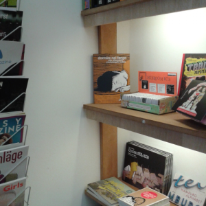 Kiste mit Minicomics in einem Regal im Buchladen