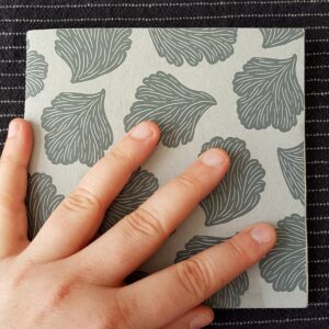 Cover des Skizzenbuches aus grauem Karton mit dekorativen Muschelformen in dunkelgrau.