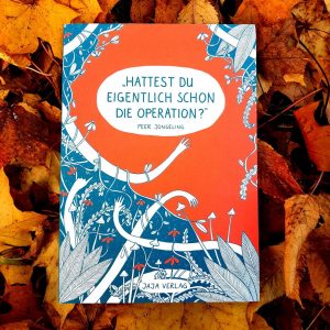 Das Buch, Hattest du eigentlich schon die Operation, mit türkisgrünem und leuchtorganenem Cover liegt auf orangegelbem Herbstlaub.