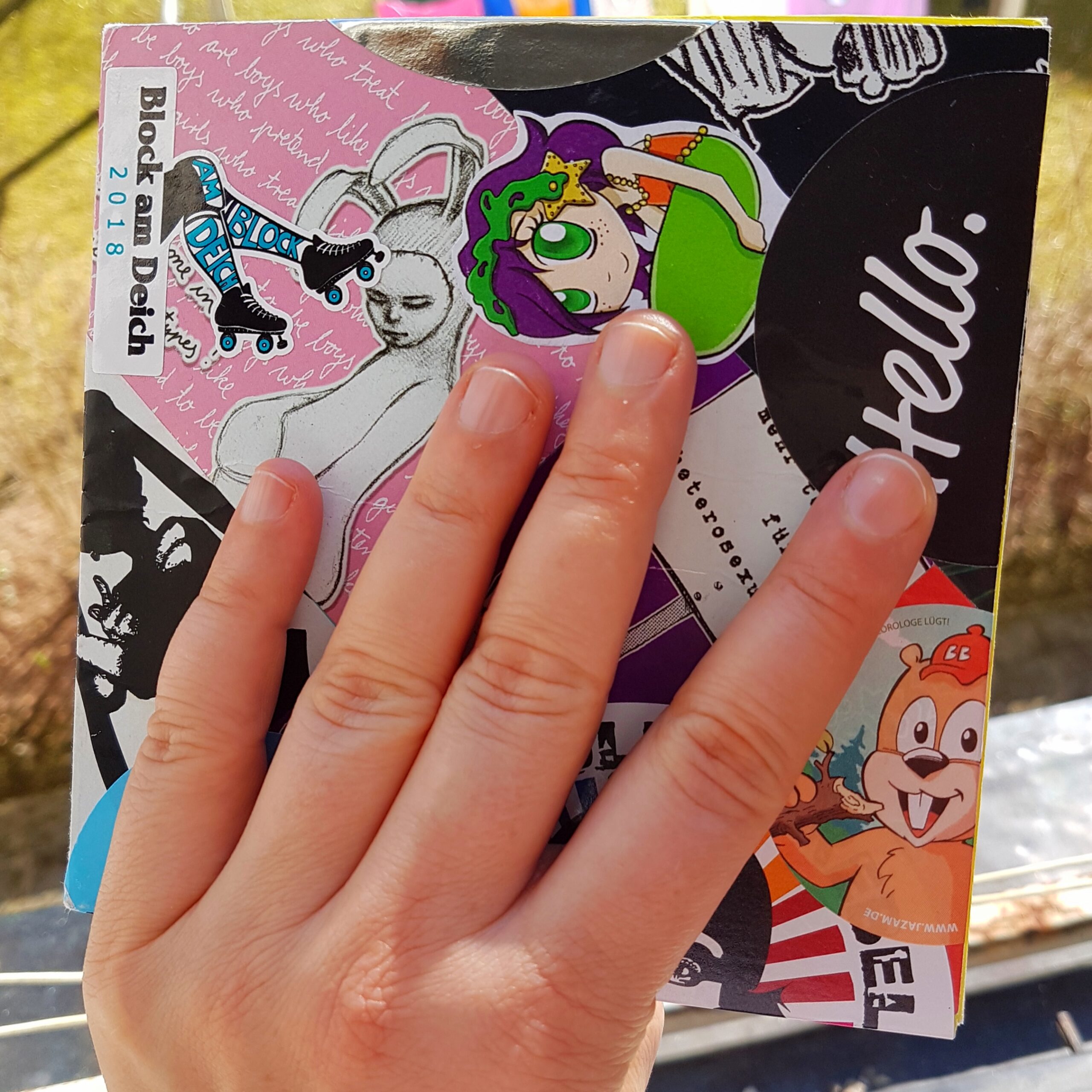 Cover vom Skizzenbuch mit übereinandergeklebten bunten Aufklebern.