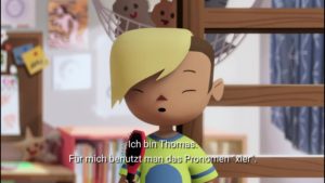 Ausschnitt des Zeichentrickfilms. Kinderzimmer mit hölzernem Stockbett und Pinnwand. Ein Kind mit Sidecut und blond gefärbter halblanger Haarmähne spricht in eine pinke Haarbürste. Die Untertitel im Bild lauten: Ich bin Thomas. Für mich benutzt man das Pronomen »xier«.