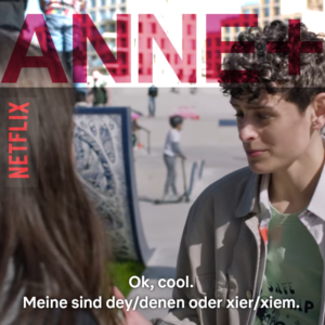 Filmstandbild mit Untertiteln aus Anne+ auf Netflix: Eine weisse Person mit kurzen braunen Locken mit ner beigen Jacke spricht mit einer Person mit langen glatten braunen Haaren deren Hinterkopf am Bilrand zu sehen ist. Die Untertitel lauten: Ok, cool. Meine sind dey/denen oder xier/xiem.