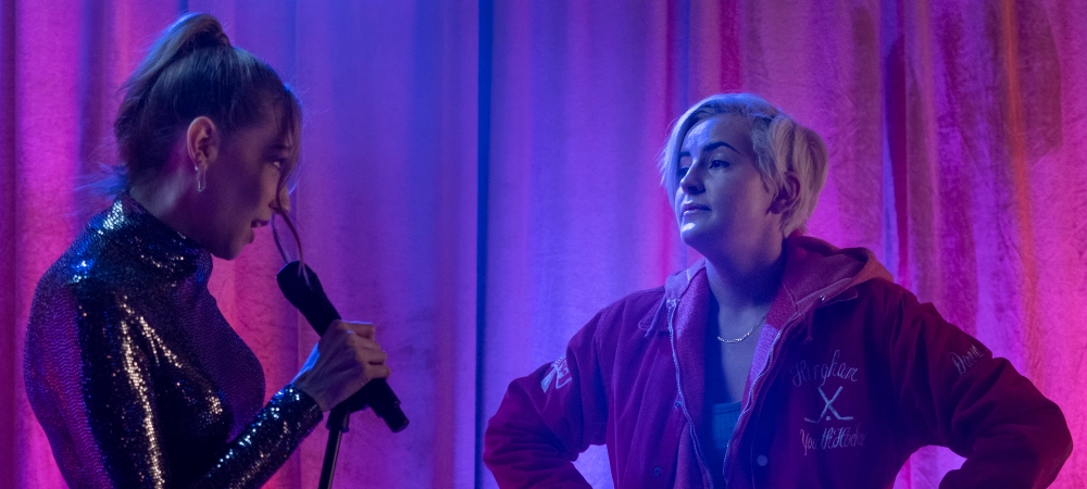 Screenshot aus der Serien, bei pink blauer Partybeleuchtung stehen sich Tess im silbernen Paillettenkleid und Finley mit rotem Hoody gegenüber und schauen sich an.