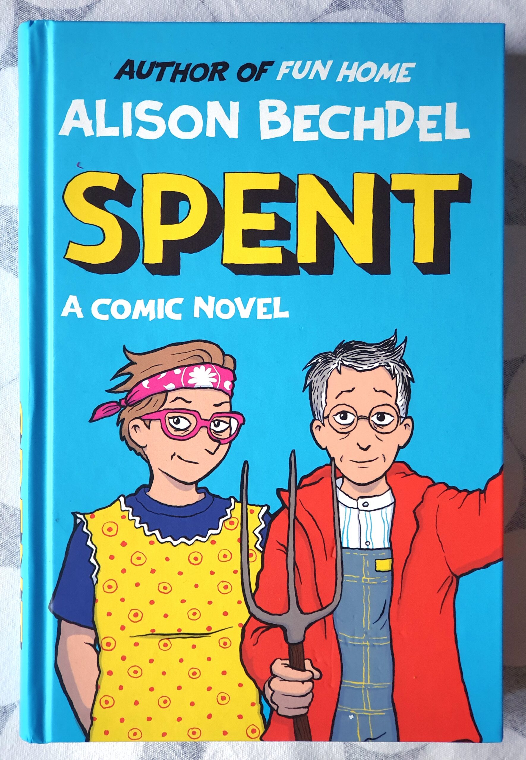 Das Buchcover des englischen Comics "Spent - A comic novel" von Alison Bechdel, Author of Fun Home. Bechdel mit einer Heugabel und ihre Freundin Holly stehen nebeneinander mit Farmklamotten, ähnlich der dörflichen Idylle in "American Gothic" von Grant Wood.