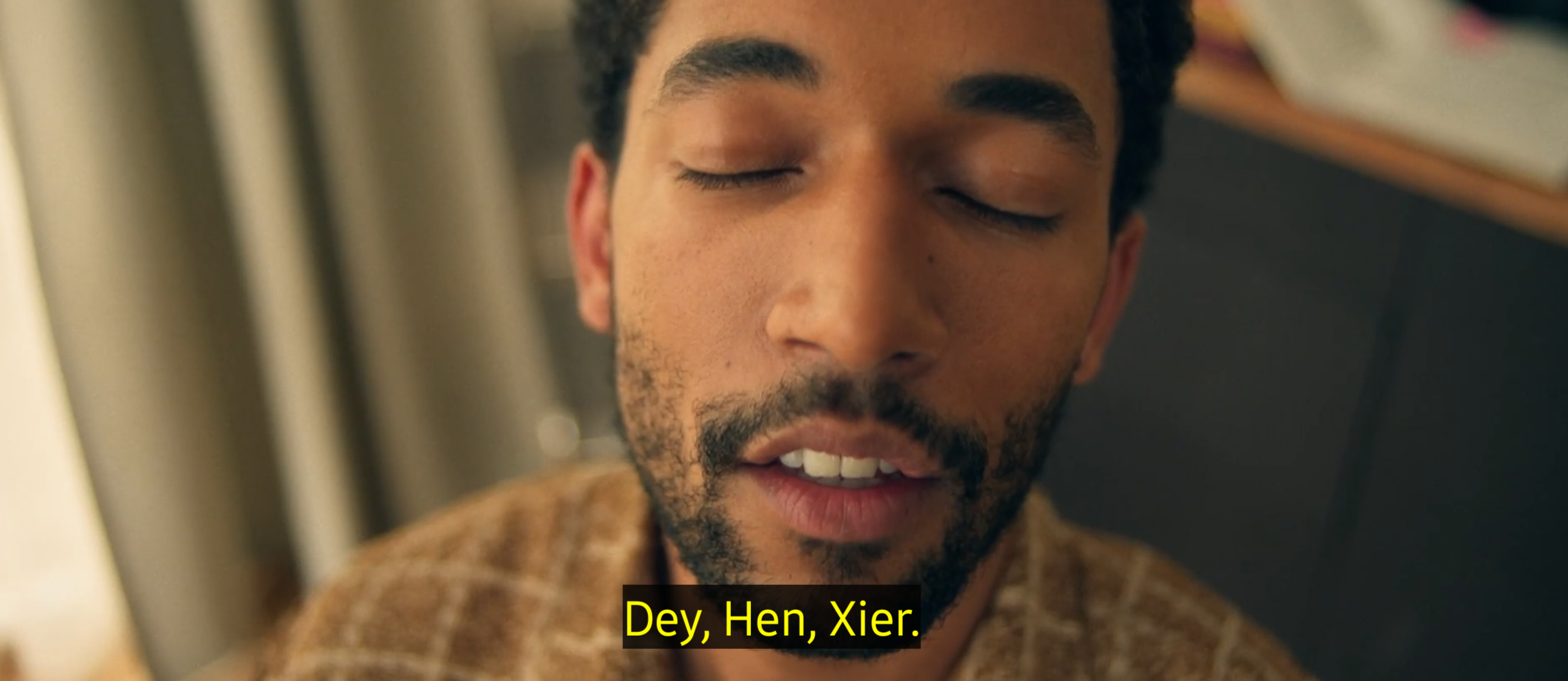 Grossaufnahme des Gesichtes einer Person mit kurzem Bart, kurzen Haaren und geschlossenen Augen. Untertitel: dey, hen, xier.